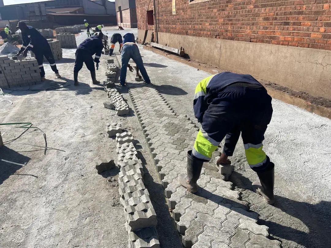 Construction team carefully laying paving blocks by hand